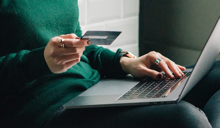 Young and smiling pretty woman using credit and laptop for online shopping at home